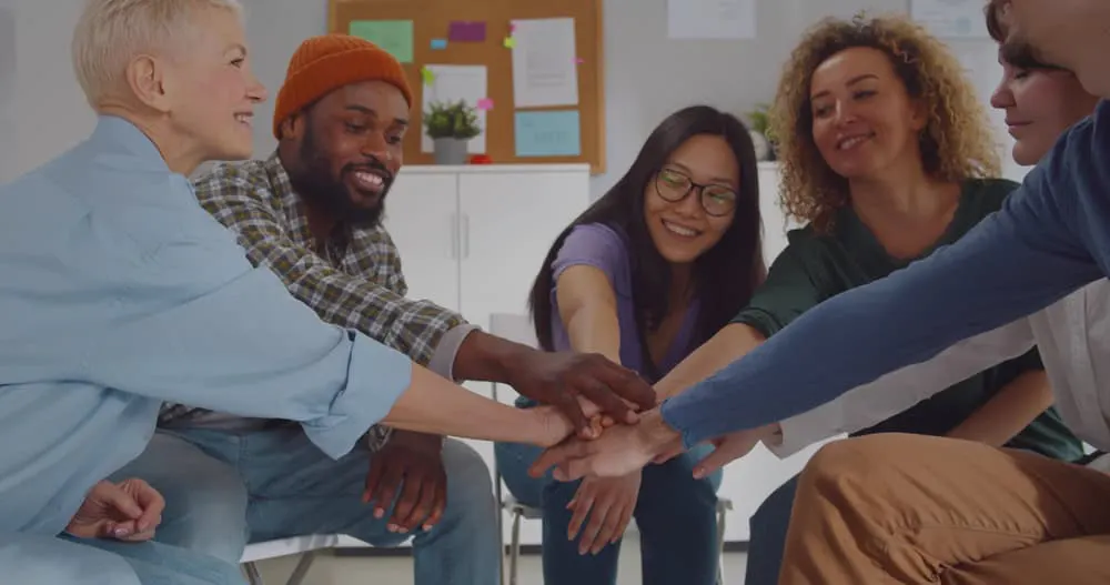 Multiracial group celebrating progress in holistic treatment for substance abuse and rehabilitation during a therapy session