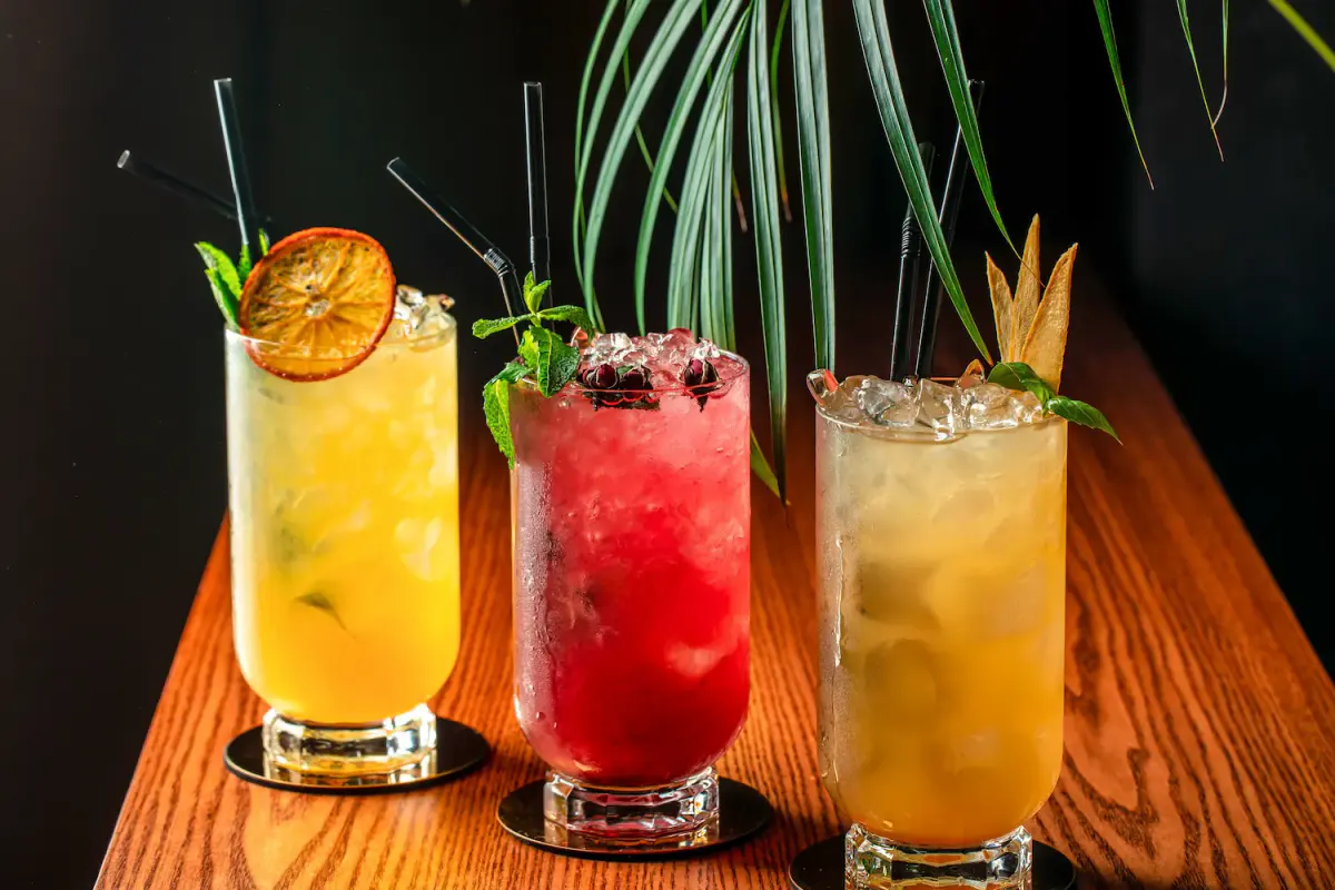 Three colorful, refreshing mocktails garnished with fruit and mint, ideal for a sober Halloween party