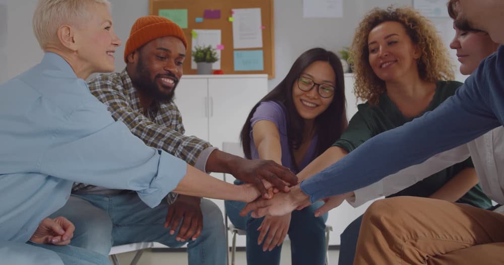 Multiracial group celebrating progress in holistic treatment for substance abuse and rehabilitation during a therapy session