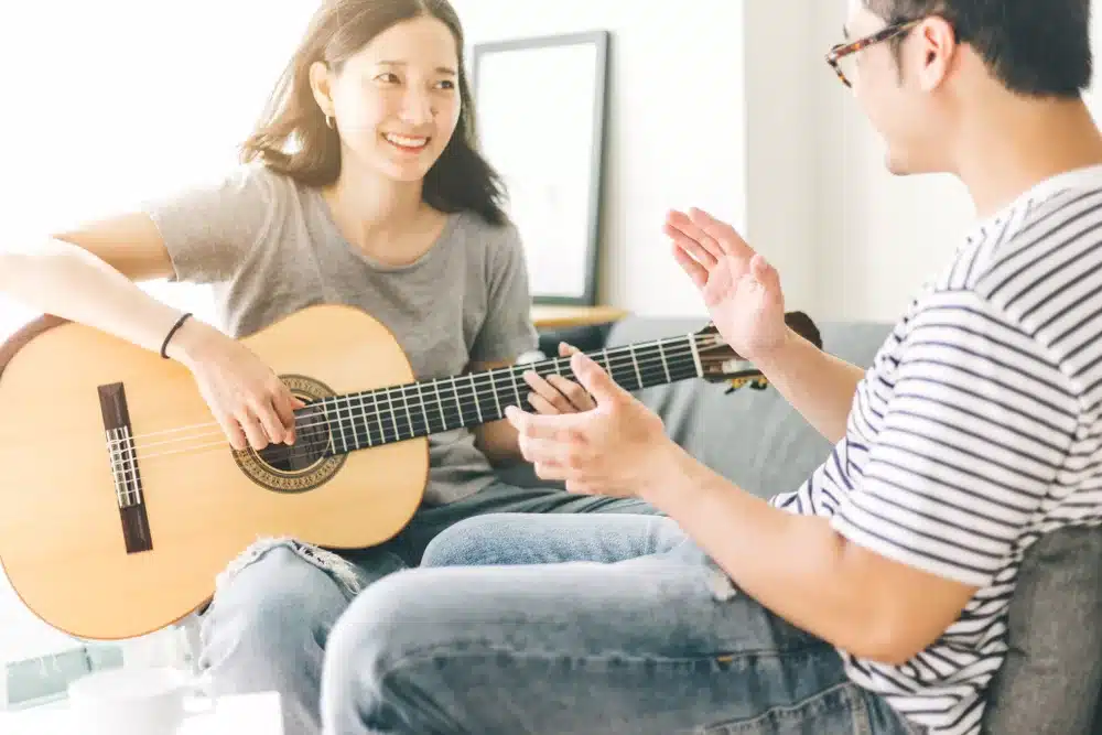 Music therapy as an effective method for addiction recovery showcasing a couple enjoying and playing acoustic guitar together at home