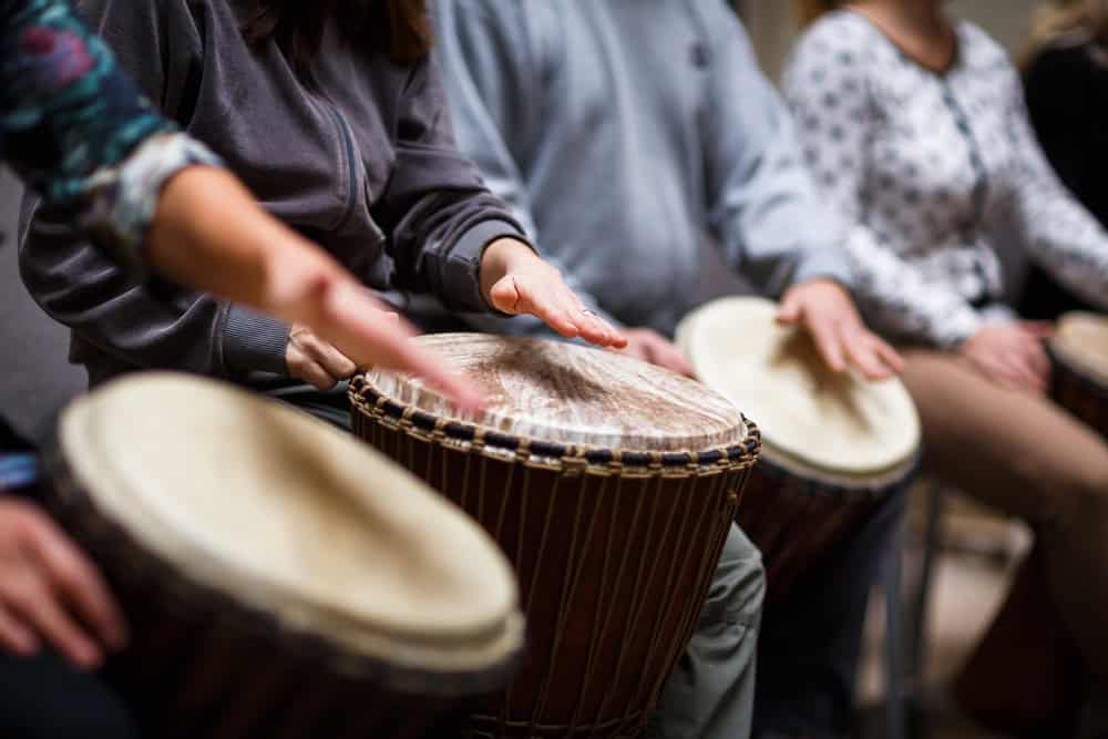 Music therapy techniques in addiction recovery showing a group of people engaged in drumming