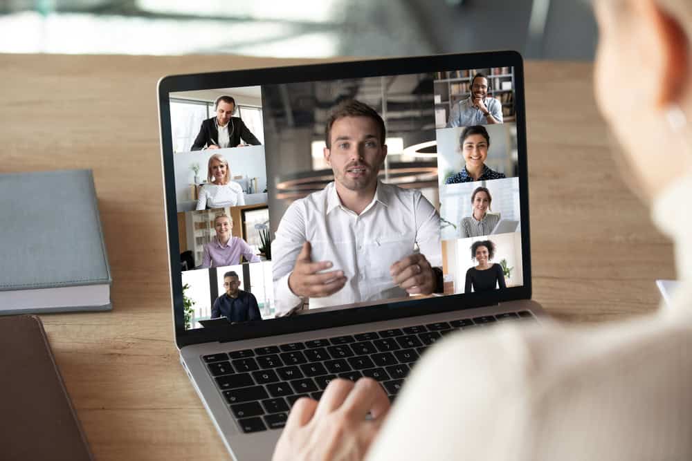 Woman engaged in online support groups discussing substance abuse emphasizing the ease of access while brainstorming on a video call with diverse colleagues