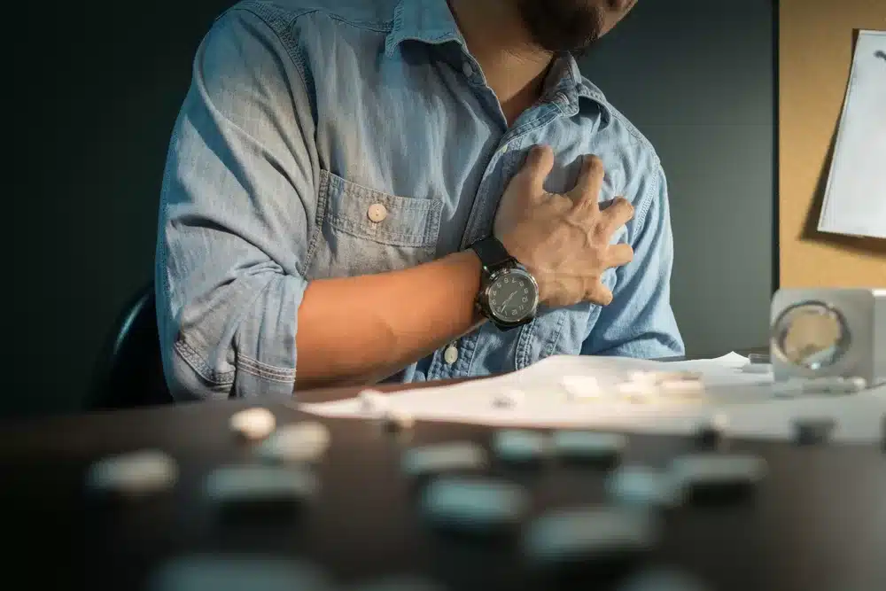 Bearded Asian male showcasing the health hazards and addiction risks of designer drugs with medicine spilling on table