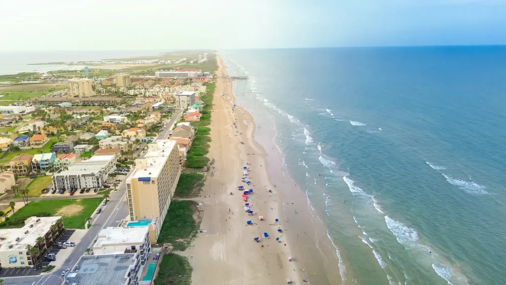 Aerial view of a crowded South Padre Island beach during Texas Spring Break 2026, featuring high-rise hotels and the Gulf Coast shoreline.