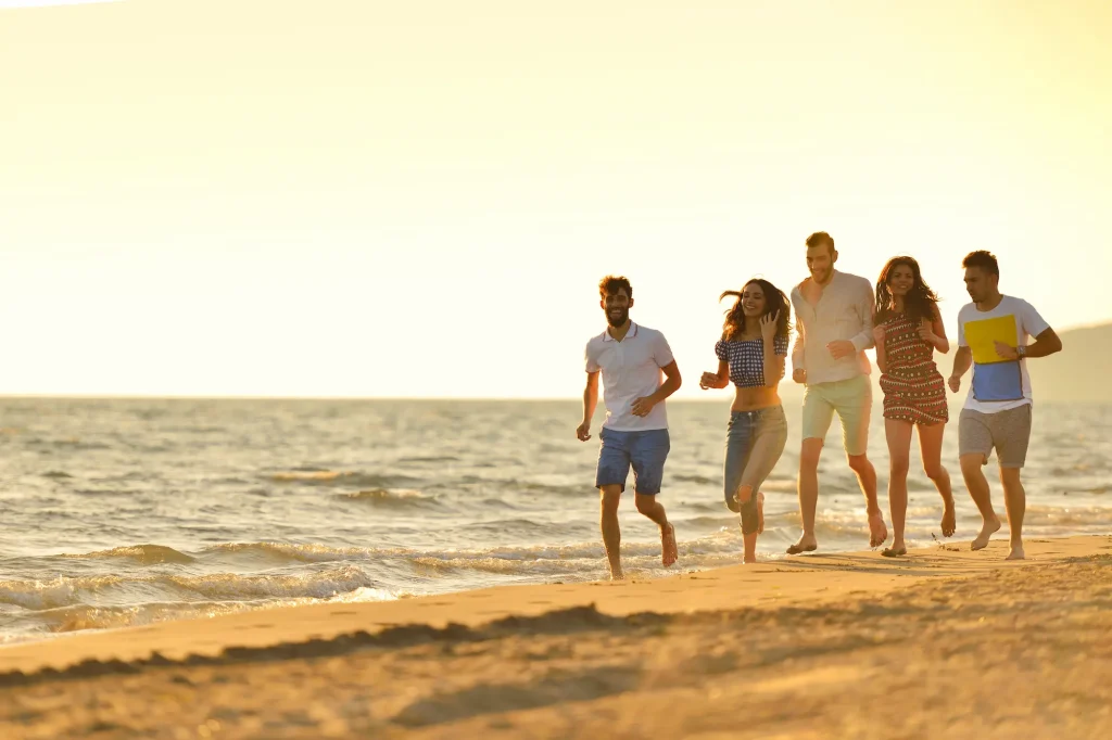 A group of happy friends running along the Texas Gulf Coast at sunset, showcasing the joy of sober travel and healthy Spring Break activities.